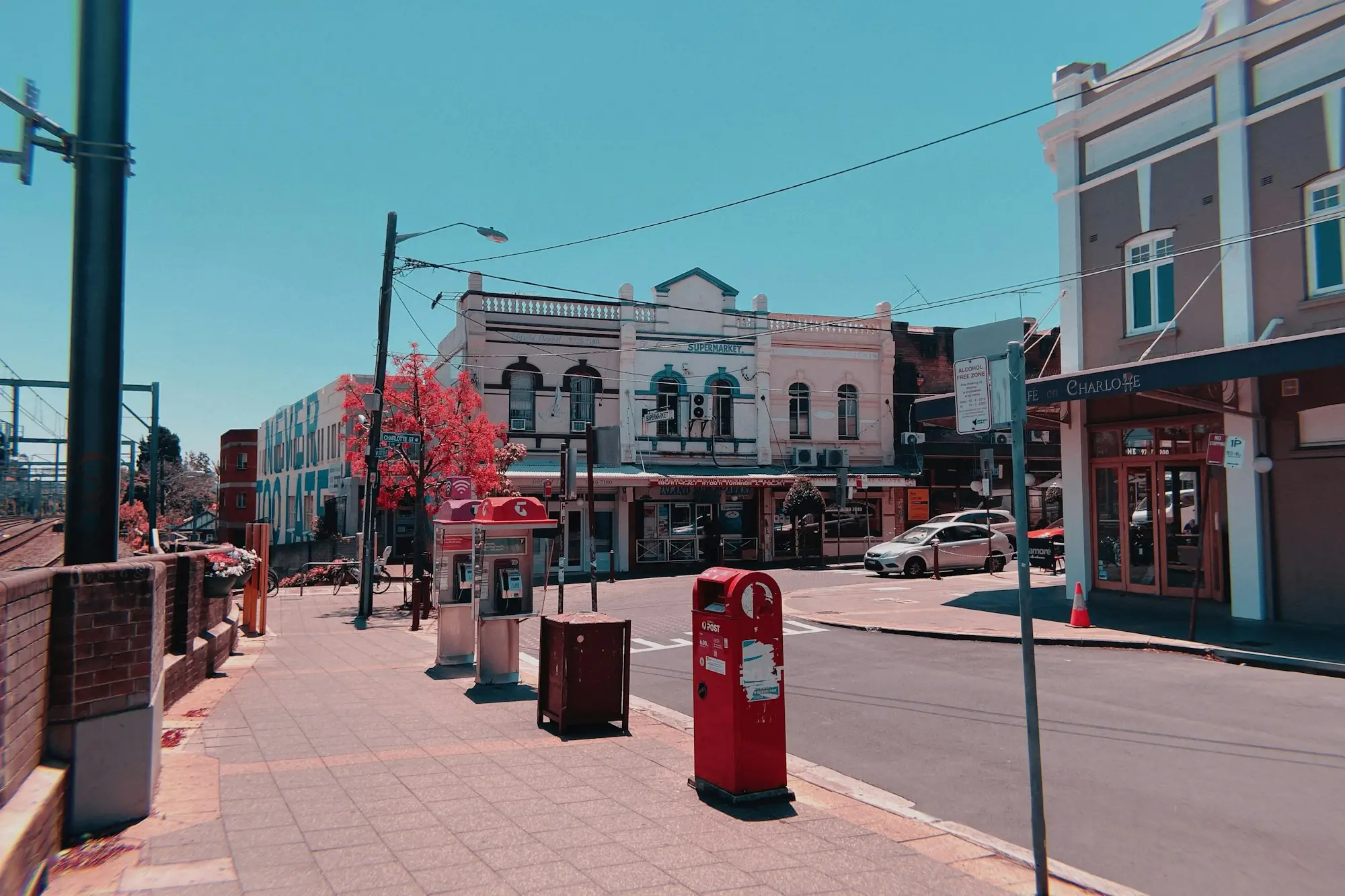 A row of independent shopfronts with awnings on an Australian suburban shopping strip with a red post box on the footpath.