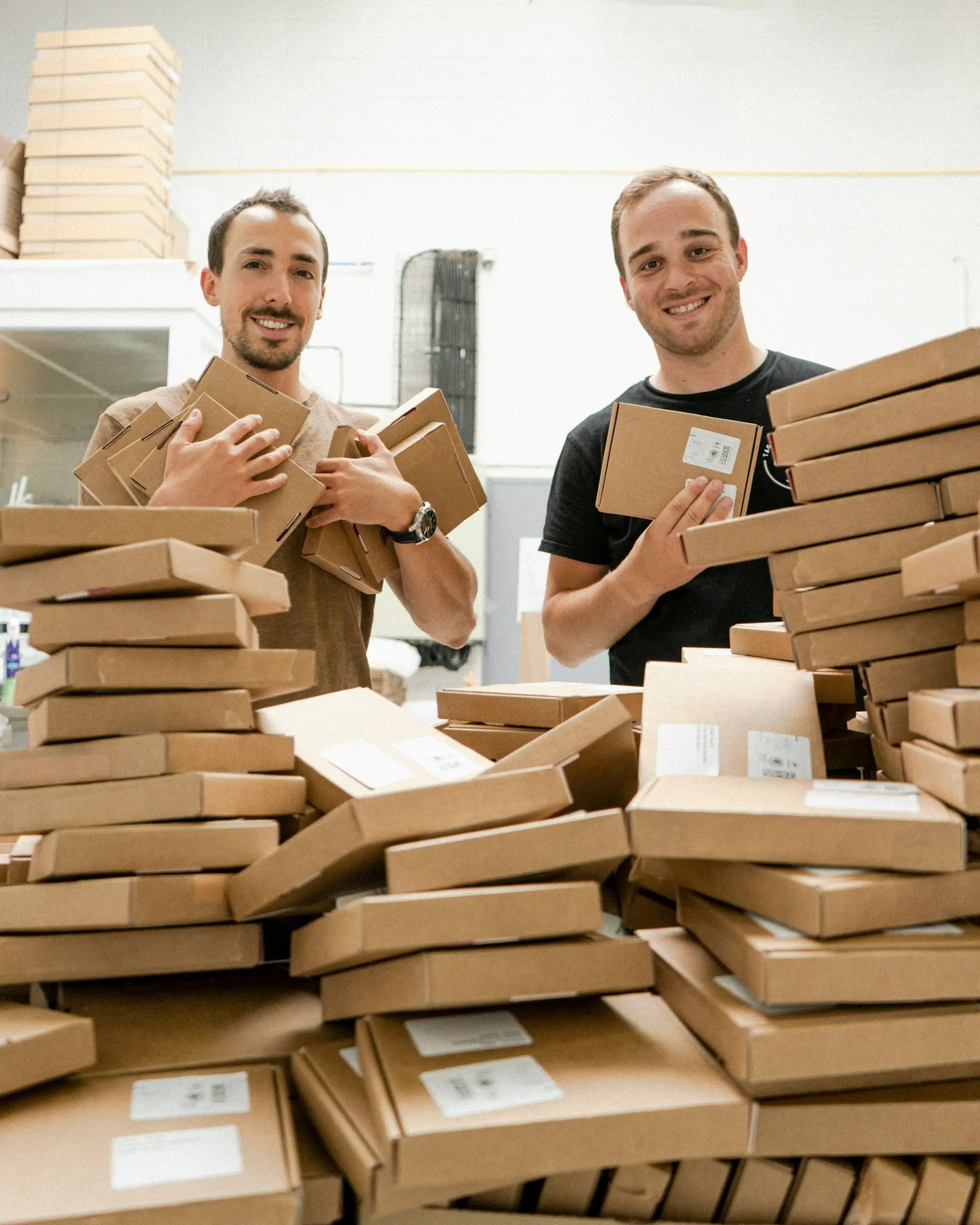 Two small business owners standing beside stacks of boxes and parcels ready for dispatch.