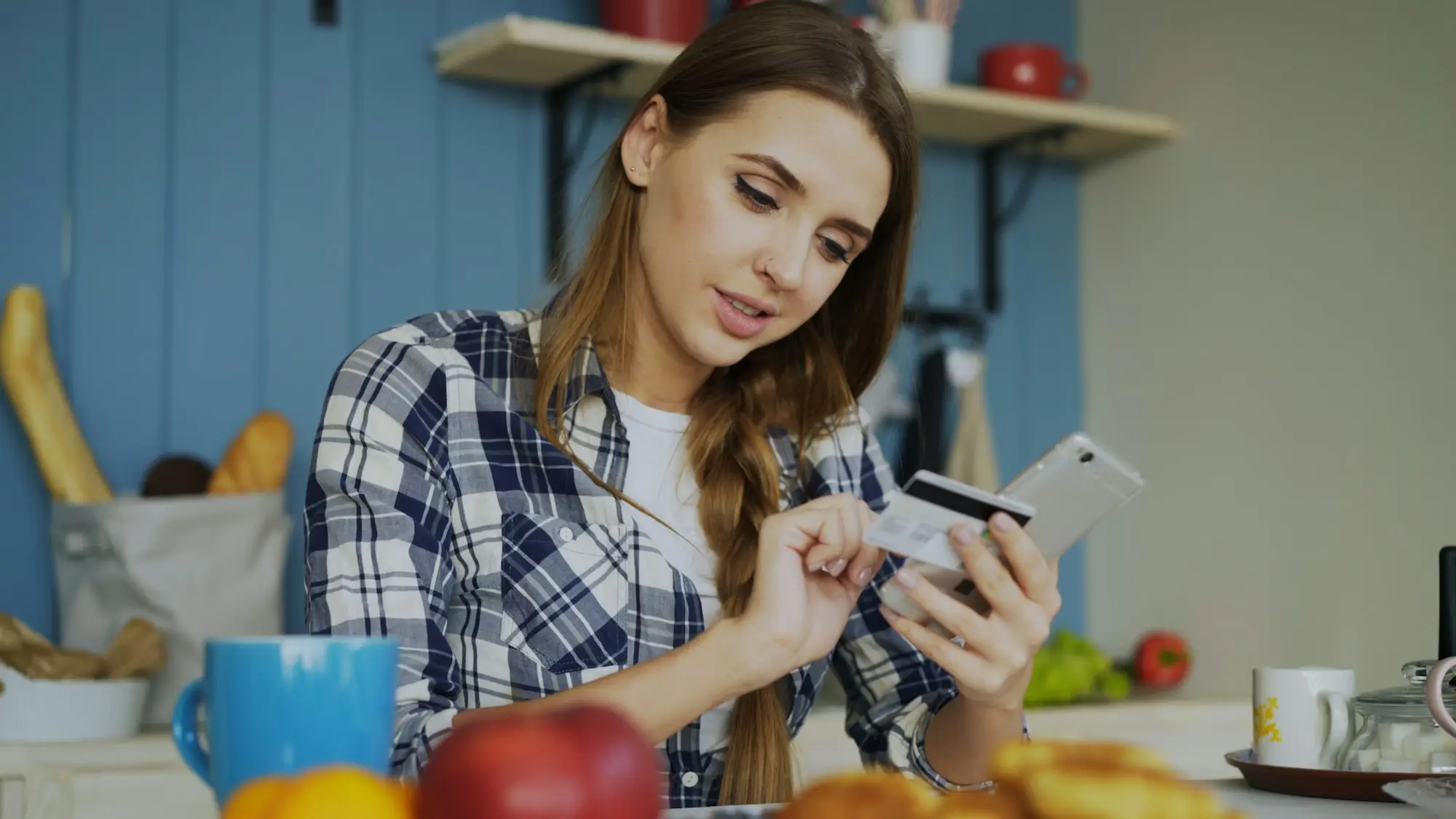 A small business owner at the kitchen table with a mug, looking over household and business bills.